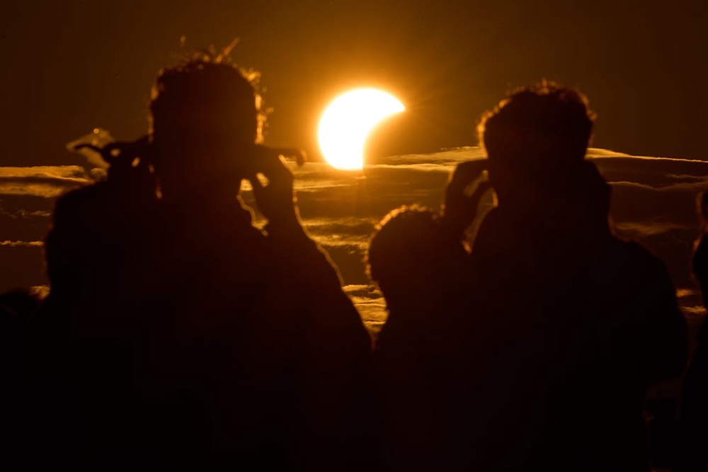 People watch a solar eclipse on the shore of the Gulf of Finland in St. Petersburg, Russia