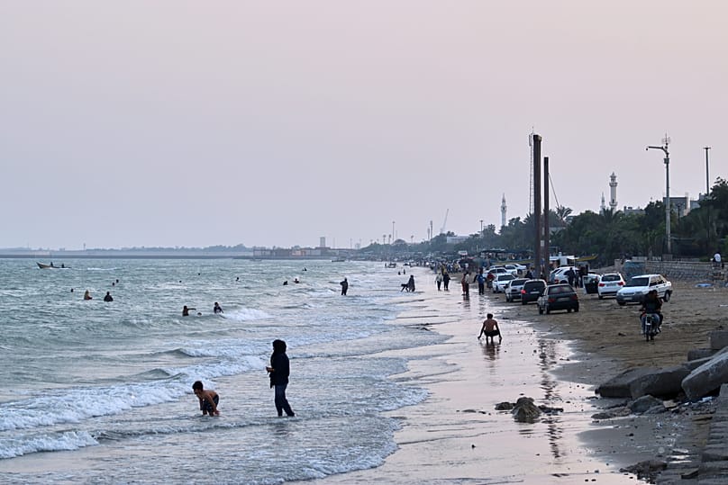 People swim and spend time along the shore of the Strait of Hormuz, off Bandar Abbas, Iran, Sunday, July 12, 2026.