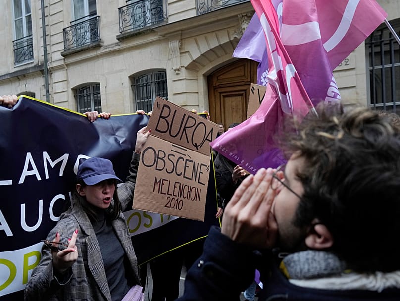 Nemesis founder Alice Cordier protests against a conference by Jean-Luc Mélenchon at Sciences Po in Paris on 22 April 2024, holding a sign reading 