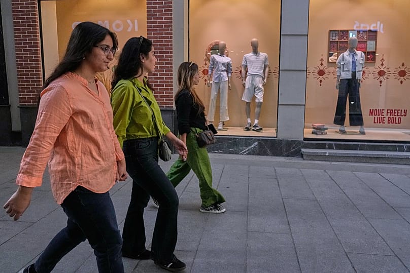 FILE: People walk past the windows of a clothes shop at a market in northern Tehran, 20 August 2026