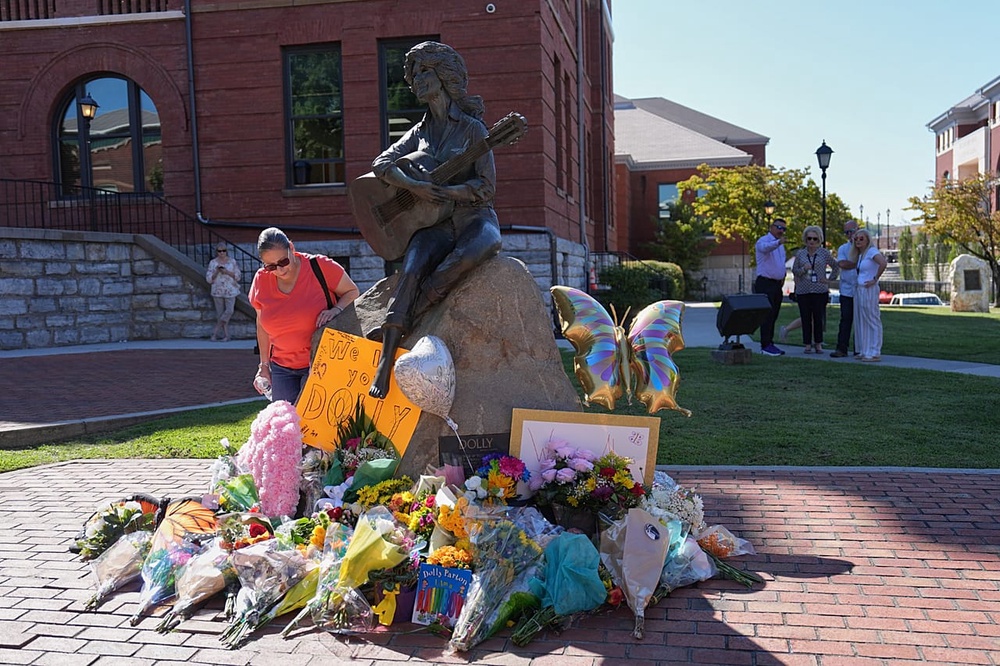 People gather at a makeshift memorial honouring Dolly Parton in front of her statue in Sevierville, Tenn., 25 August 2026.