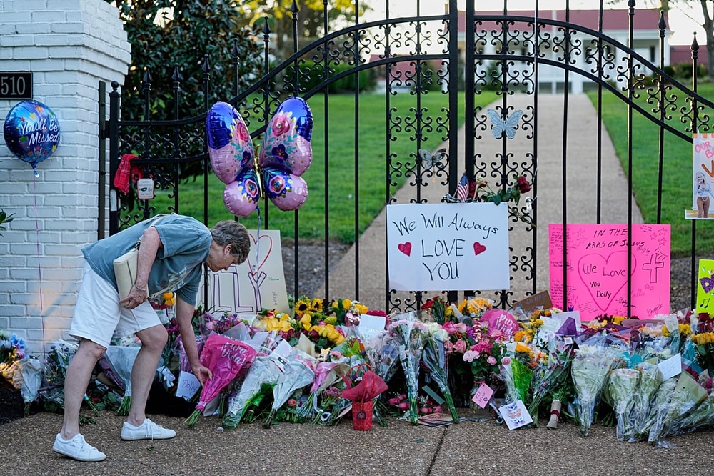 A fan leaves flowers for a makeshift memorial honouring Dolly Parton outside her home, 25 August 2026, in Brentwood, Tenn. 