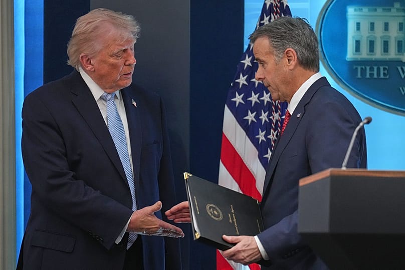 Donald Trump shakes hands John Ratcliffe as they speak with reporters in the James Brady Press Briefing Room at the White House, April 6, 2026, in Washington
