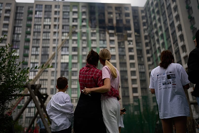 Locals watch as firefighters work after a Russian drone attack struck a residential building in Kyiv, 1 September, 2026