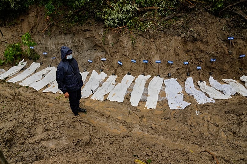 A Nepali police official stands next to a row of bodies of flash flood victims laid in a mass grave for burial in Kathmandu, Nepal, Tuesday, Sept. 1, 2026. 