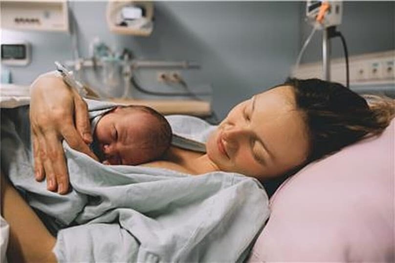 A mother hugs her newborn baby in hospital shortly after giving birth.