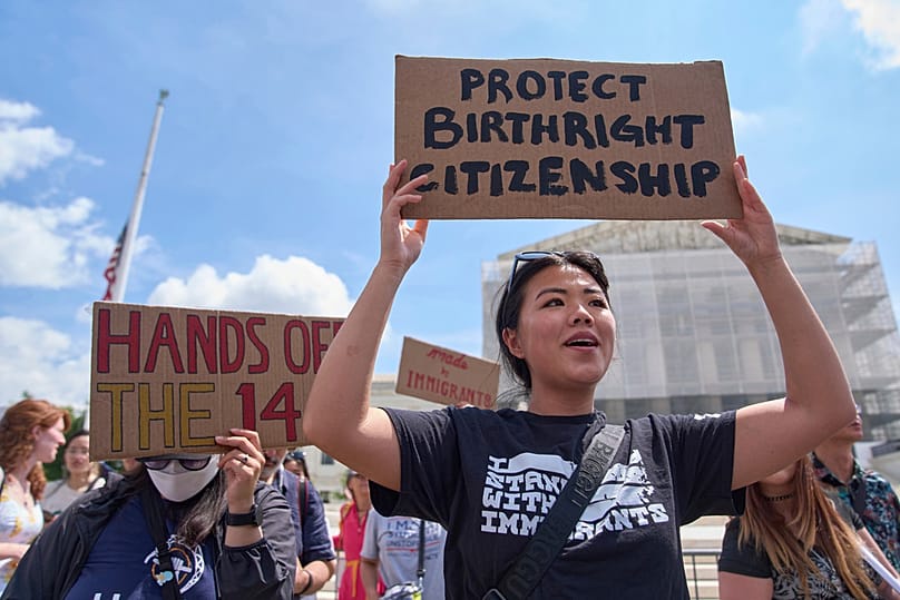 FILE - Hannah Liu, 26, of Washington, holds up a sign in support of birthright citizenship, May 15, 2025, outside of the Supreme Court in Washington