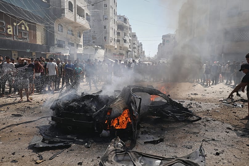 Palestinians gather around the burning wreckage of a car after an Israeli army strike in Gaza City, 31 August, 2026