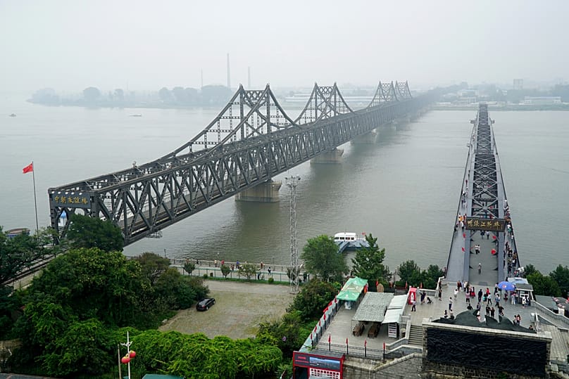 Visitors walk across the Yalu River Broken Bridge next to the Friendship Bridge connecting China and North Korea in Liaoning province, 9 September, 2017