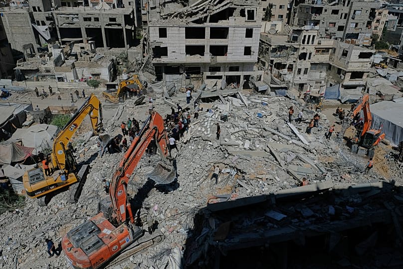 Palestinian civil defense crews search for bodies and survivors in the rubble of a collapsed building that housed displaced Palestinians and was heavily damaged.