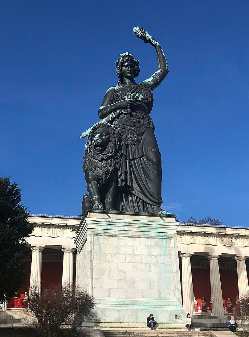 The Bavaria statue, unveiled in 1850, towers over the Theresienwiese and is considered a symbol of Bavaria, with the Hall of Fame in the background.