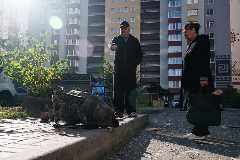 Local residents look at fragments of Shahed drone near a multi-storey residential building damaged following a Russian strike, in Kyiv, Ukraine.