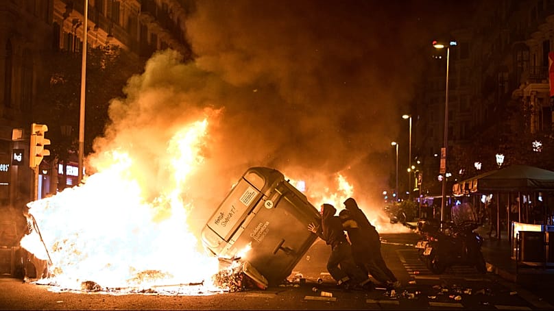 Protesters set rubbish bins on fire during clashes with police in Barcelona, Spain, on Monday 5 October 2026. 