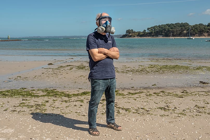 Environmental activist Yves-Marie Le Lay demonstrates the the mask he wears when algae reaches dangerous levels at at Plage du Fond de la Baie, in Locquirec, Brittany.