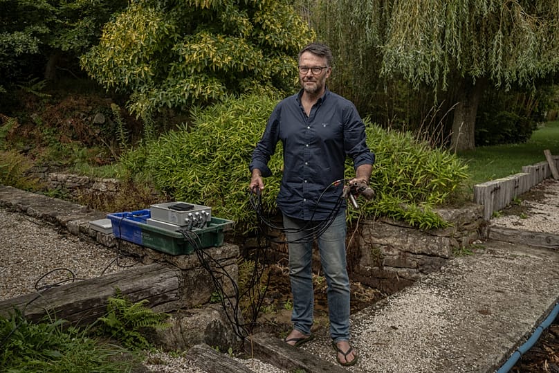 Fabrice Hamon uses a device to test the water of the Foul River and collects regular water samples to test for e. coli.