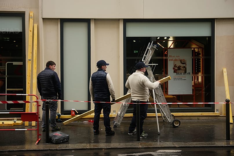 Workers board up a storefront on the eve of further protests in Paris, 23 Oct. 2026