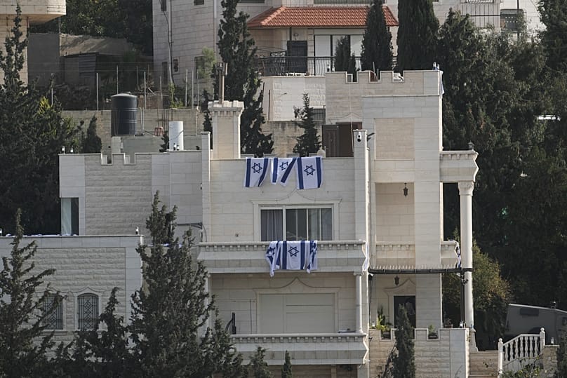 Israeli flags hang from a house belonging to Palestinian residents during an Israeli army operation in Hebron, in the occupied West Bank, Saturday, Oct. 24, 2026