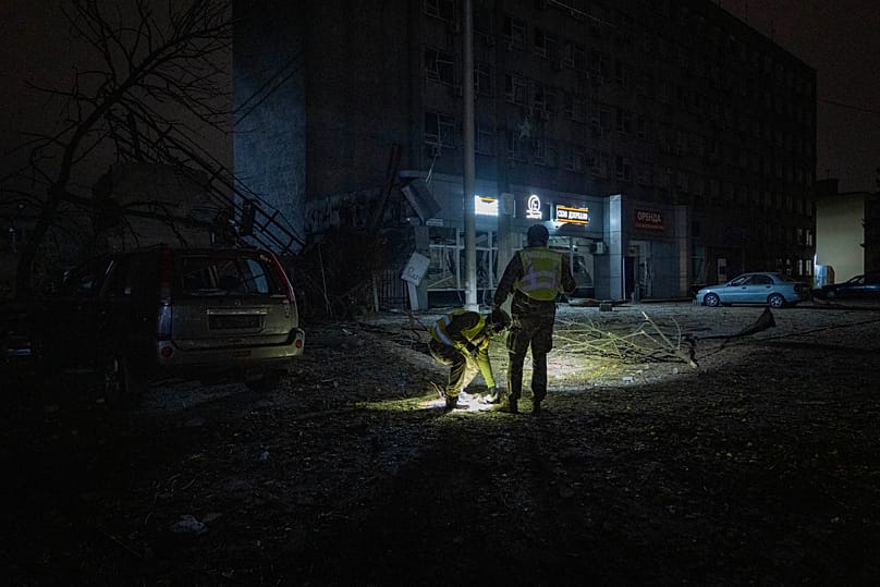 An explosive ordnance disposal technician uses a flashlight to inspect debris and a damaged building at the site of a Russian strike in Kyiv, Ukraine, Tuesday, Oct. 27, 2026. 