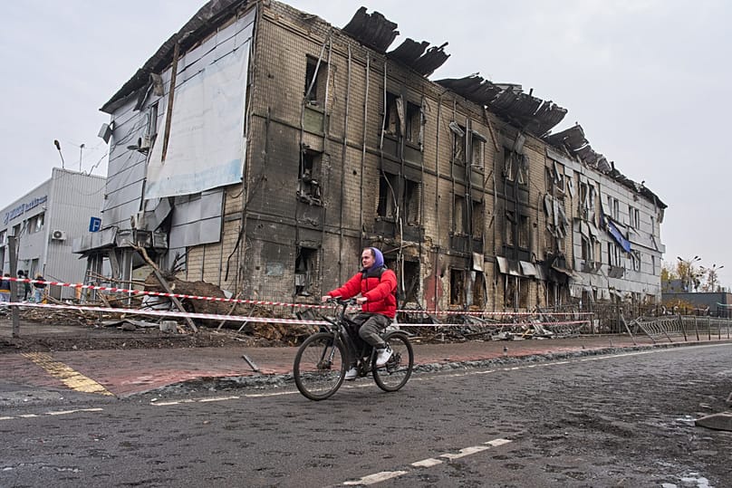 A man rides a bicycle past a building destroyed during a night-time Russian air raid in Kyiv, Ukraine, 27 October 2026.