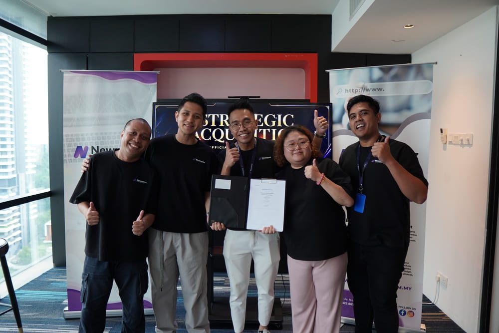 Newnormz and Weitzen team members celebrating the completion of the strategic acquisition agreement during an office signing session in Malaysia.
