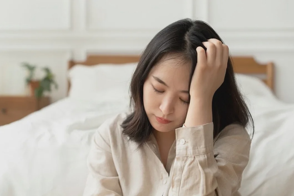 asian woman sitting sad by her bed 53876 127305