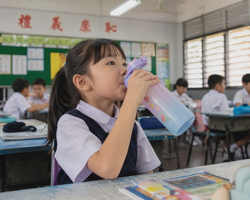 小学女生在课室里用水壶水瓶喝水