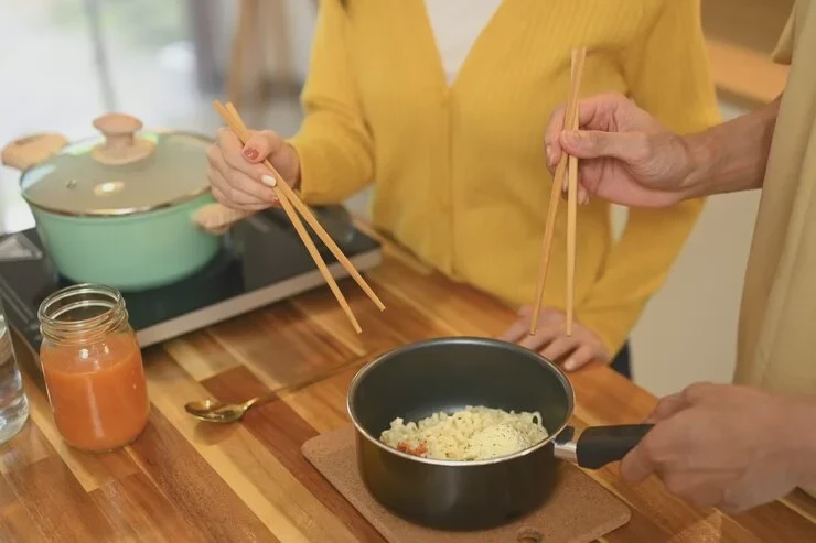 close up shot young couple sharing bowl instant noodles enjoying casual meal kitchen 35674 27599