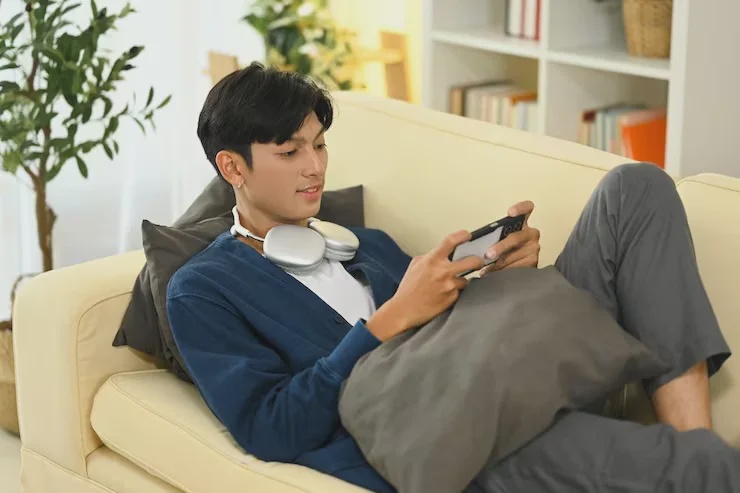 young man chilling relaxing couch playing phone