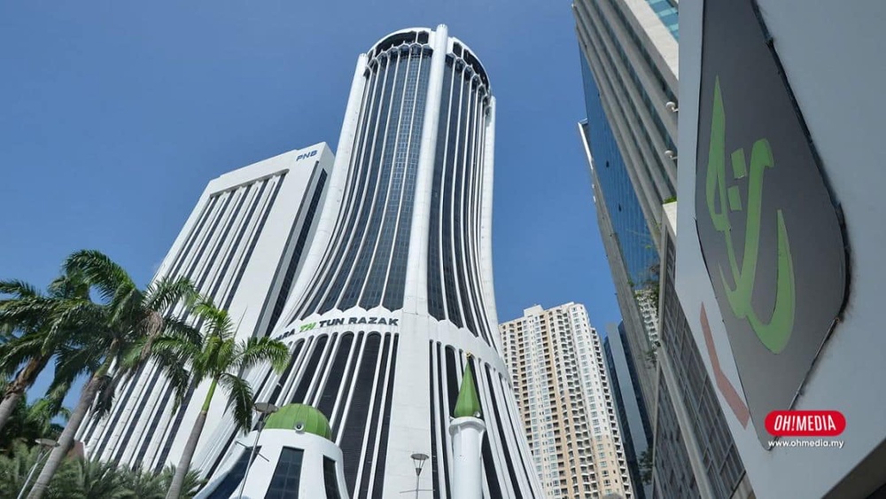 Tall white high-rise with curved vertical windows labeled Tun Razak in Kuala Lumpur, flanked by palm trees under a blue sky.