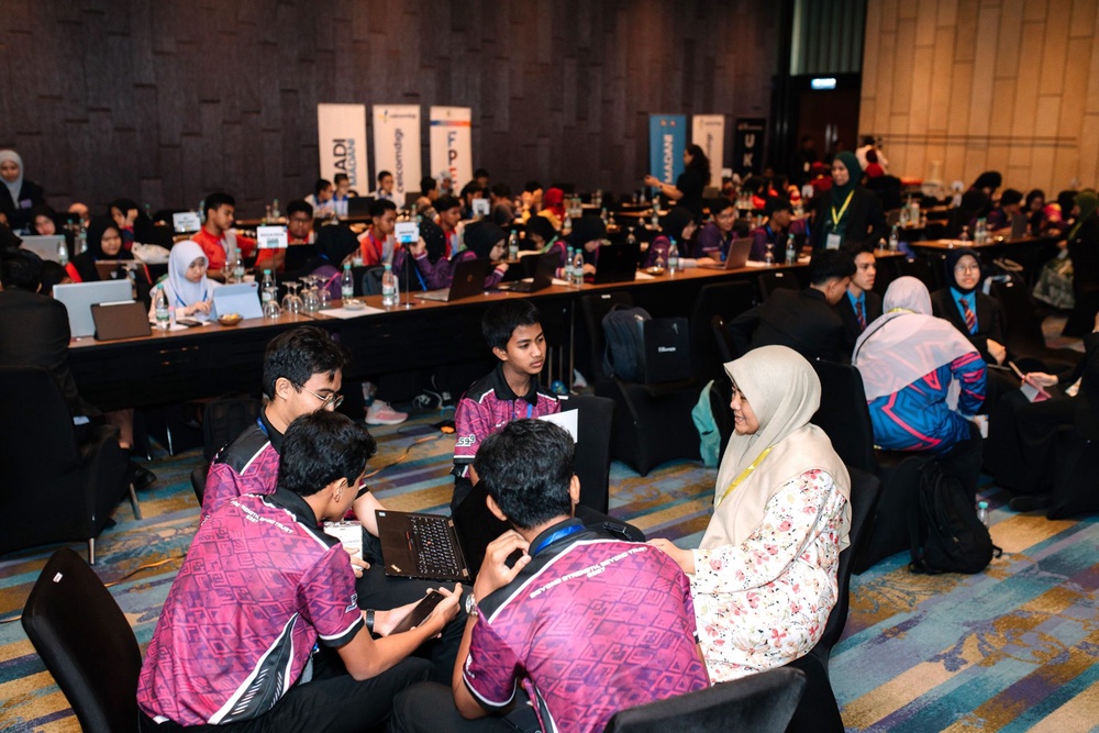 Finalist team discussing their AI project with a teacher at the AI Muda@NADI Hackathon