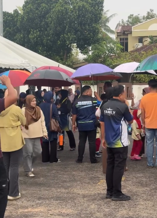 Image from: Tak Mahu Anak Basah Kena Hujan, Ibu Bapa Gabung Payung Iring Naik Bas