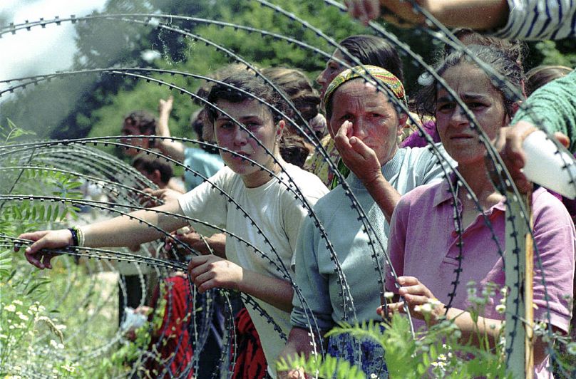 FILE: Refugees from the overrun UN safe area of Srebrenica looking through the razor wire at newly arriving refugees, in a UN base 12 kms south of Tuzla, 13 July 1995