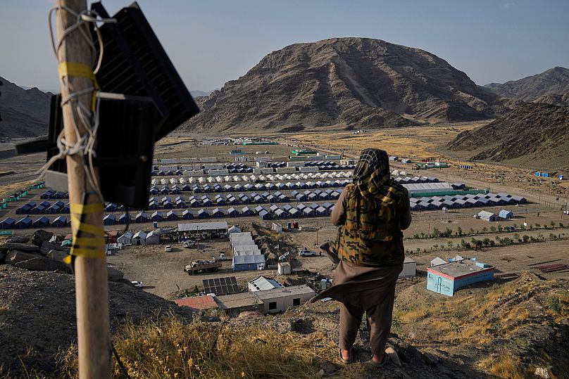 A Taliban fighter stands on a hill overlooking a camp housing Afghan refugees in Torkham, 31 May, 2025