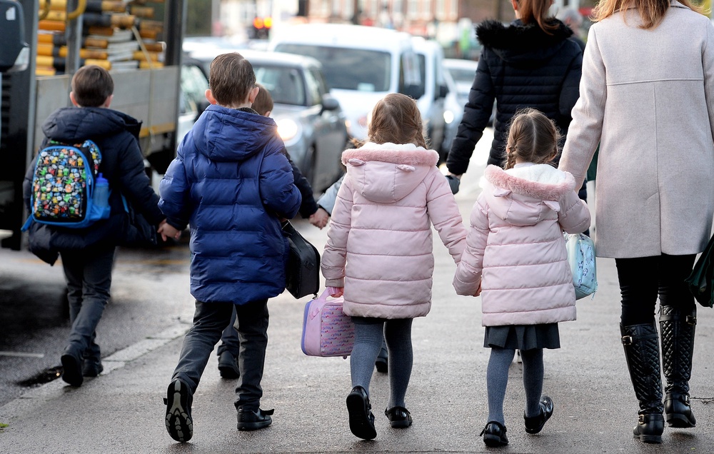Parents walk their children to school (PA)