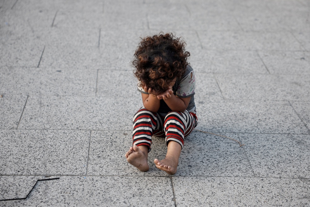 A displaced Lebanese child sits with their head in their hands amid Israel’s ongoing offensive against Hezbollah (REUTERS)