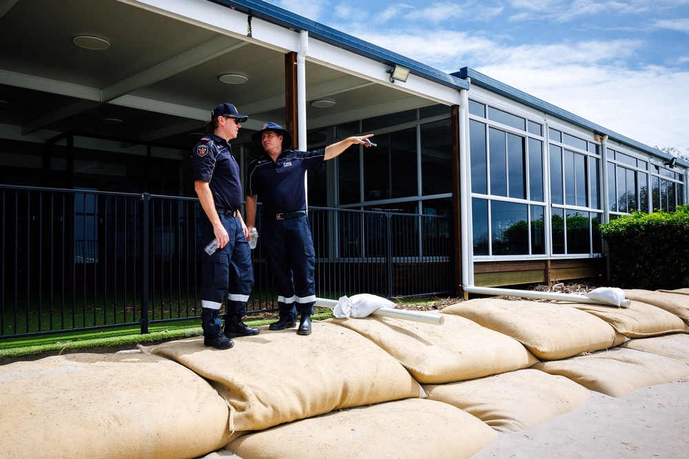 Fire and rescue personel walk past sand bags used to protect a building from the appraching tropical cyclone Alfred at Golden Beach (AFP via Getty Images)