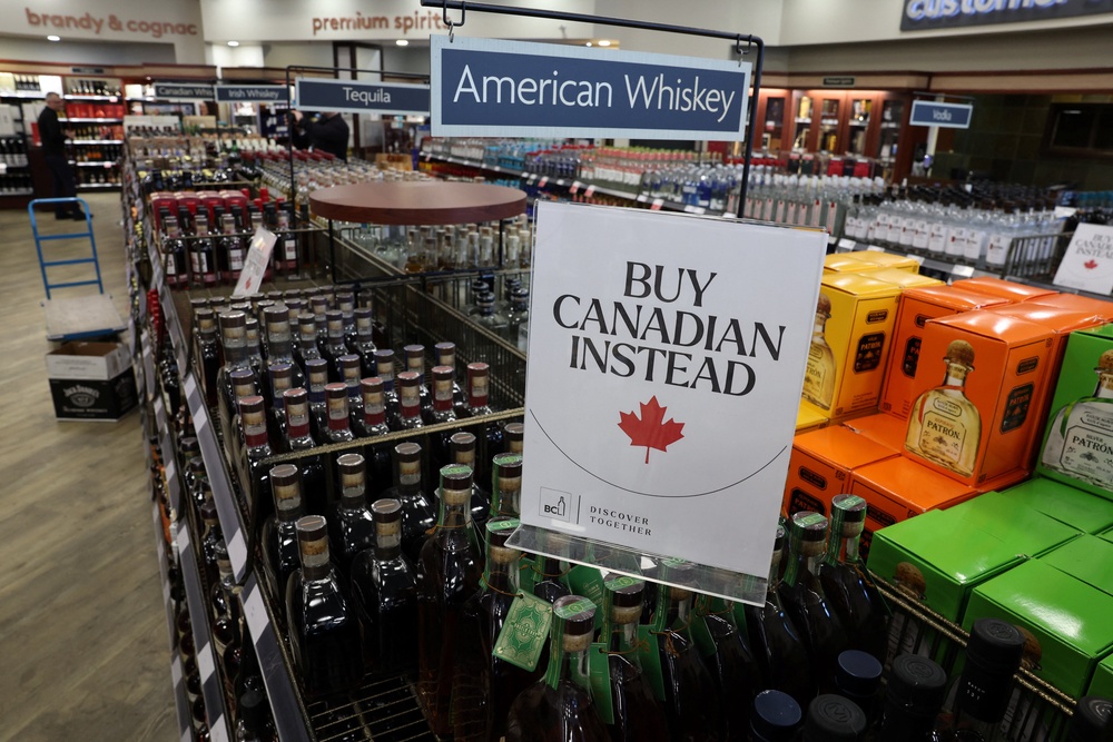 A sign that reads ''Buy Canadian Instead'' is displayed on top of bottles, hanging above another sign that reads
