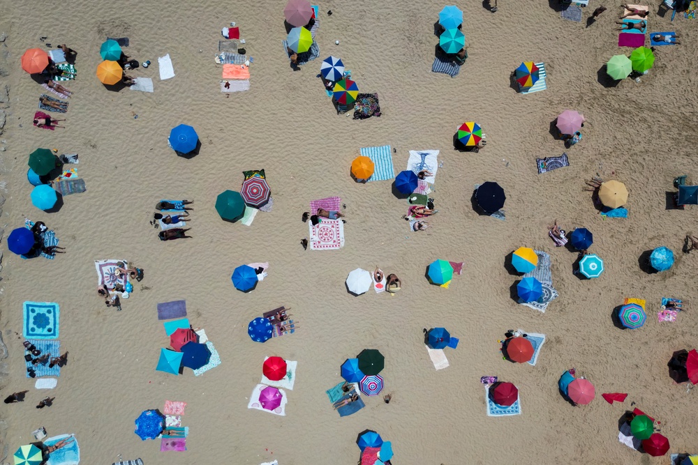People sit under umbrellas at the Costa da Caparica beach in Almada, near Lisbon on Sunday (AFP via Getty Images)