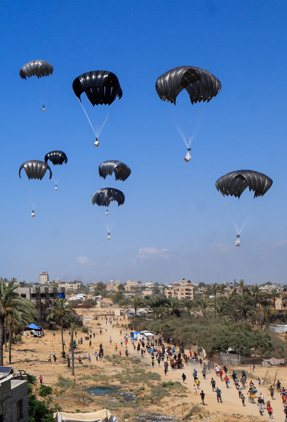 Aid packages dropped from an airplane descend over Gaza on Thursday (REUTERS)