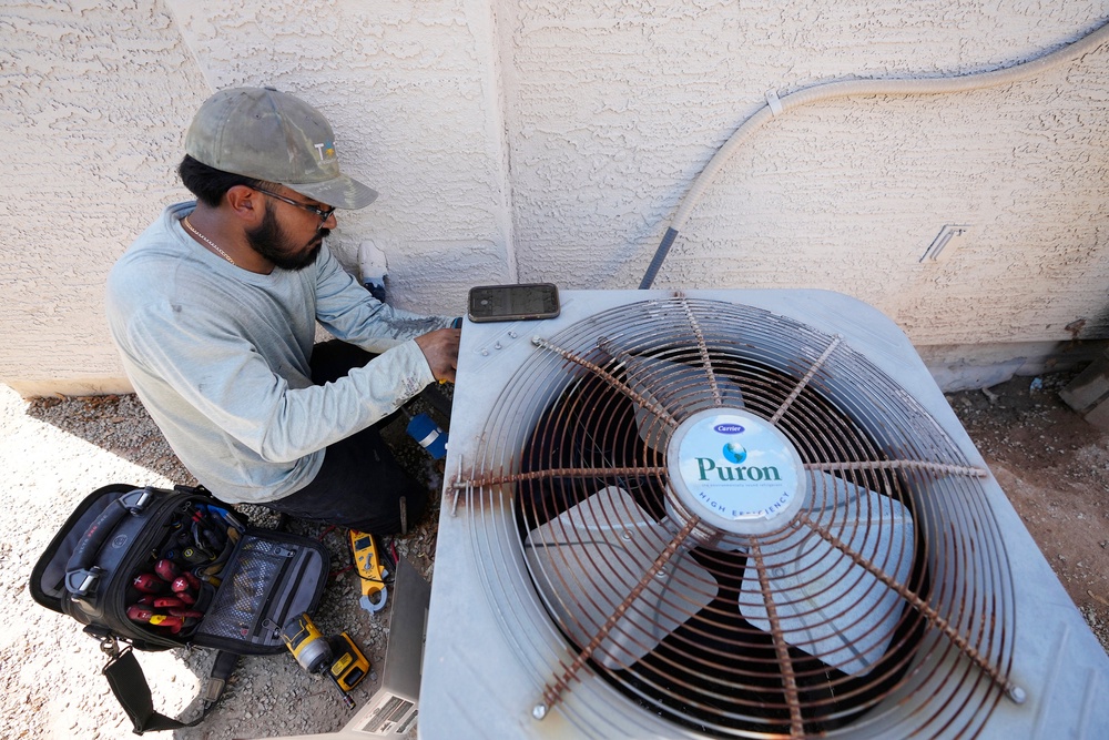Total Refrigeration service tech Michael Villa works on replacing a fan motor on an air conditioning unit (AP)