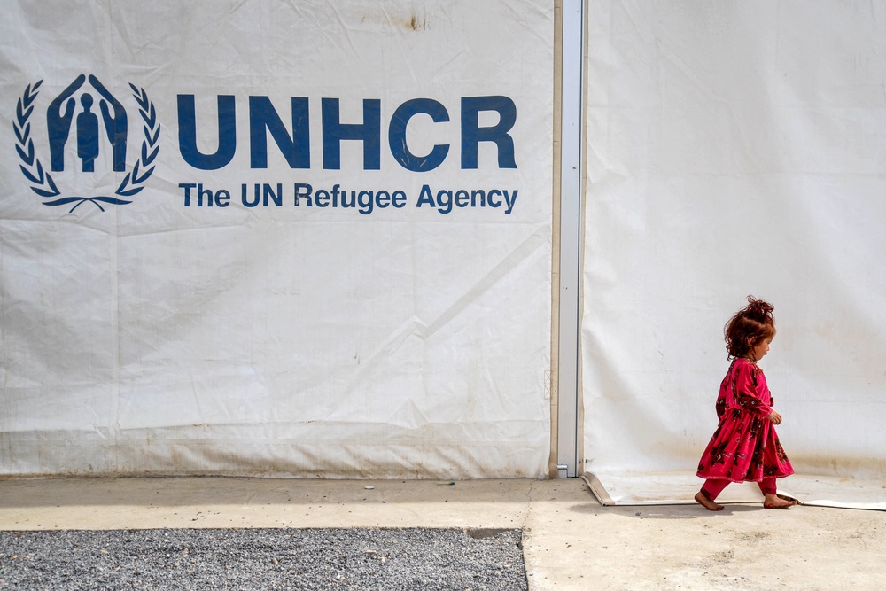 An Afghan girl walks past a registration centre with the United Nations High Commissioner for Refugees (UNHCR) signage after returning to Afghanistan from Pakistan last year (AFP/Getty)