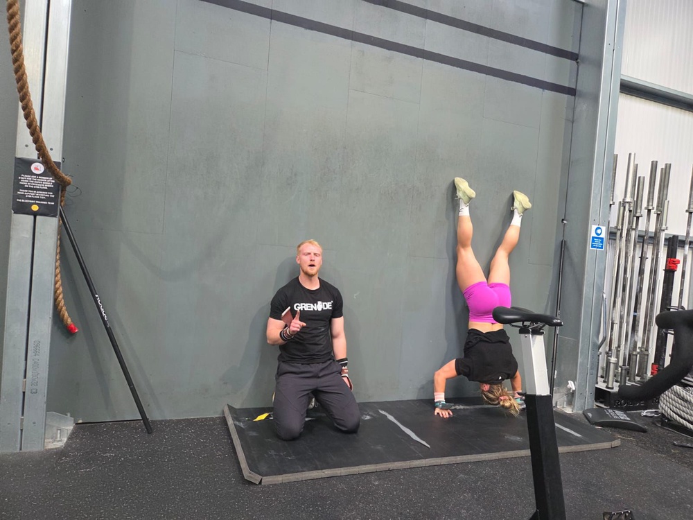 I have to scale back my handstand press-ups as Cringle breezes through her set next to me (Grenade)
