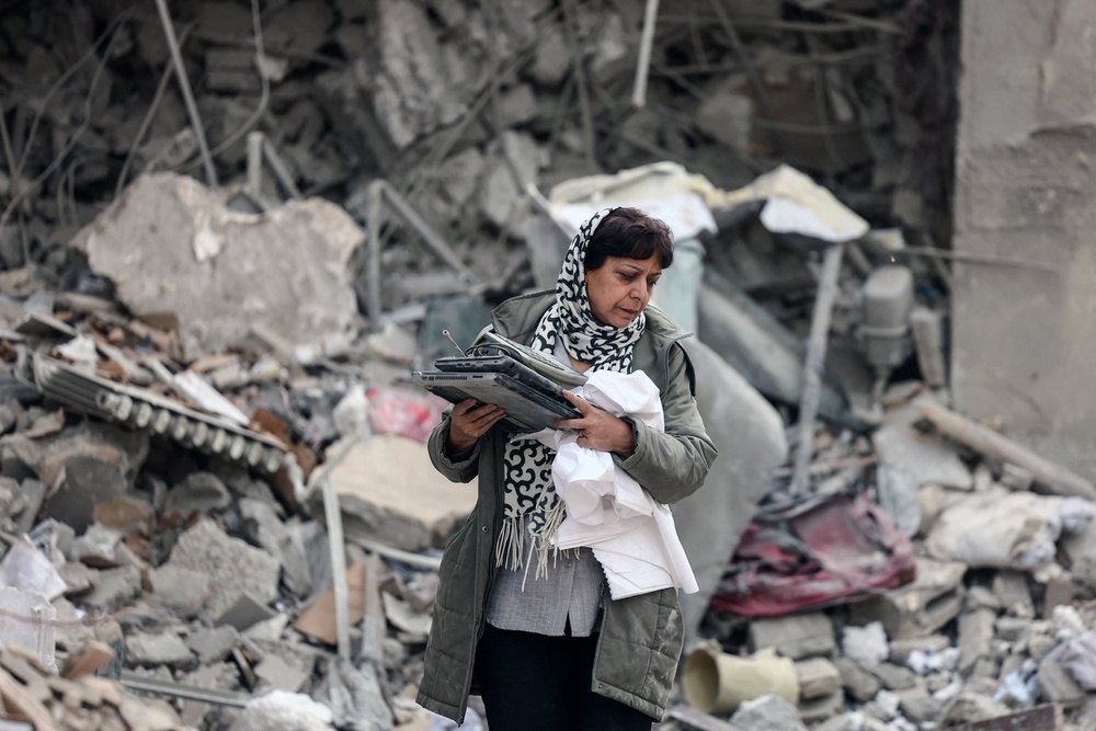 An Iranian woman collects belongings from the rubble of a destroyed residential building in Tehran on 12 March 2026 (AFP/Getty)