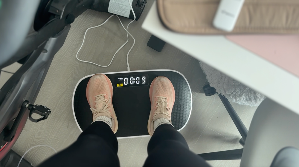 The Independent's Julia Musto stands on a vibration plate in her New York City apartment (Julia Musto/The Independent)