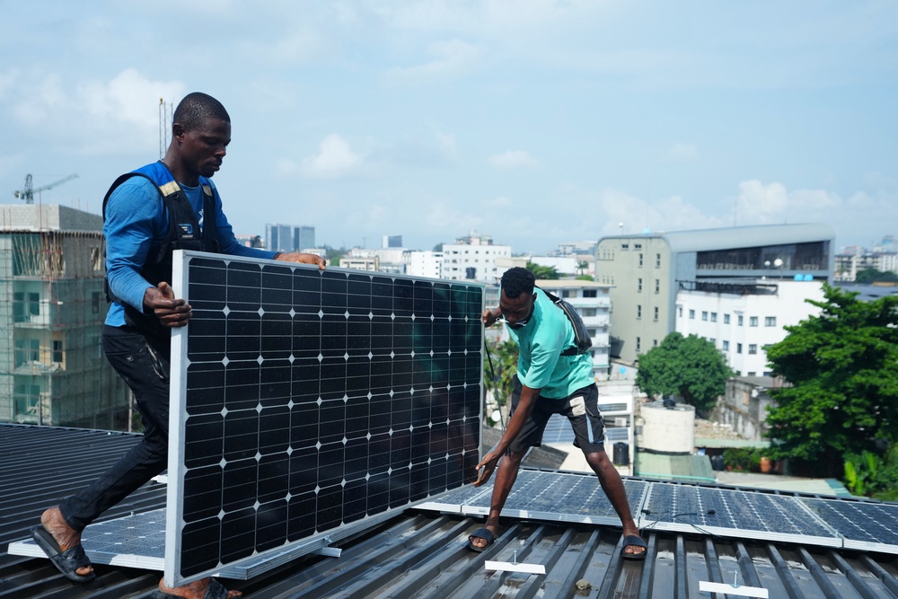 Workers install solar panels on a house roof. (AP)