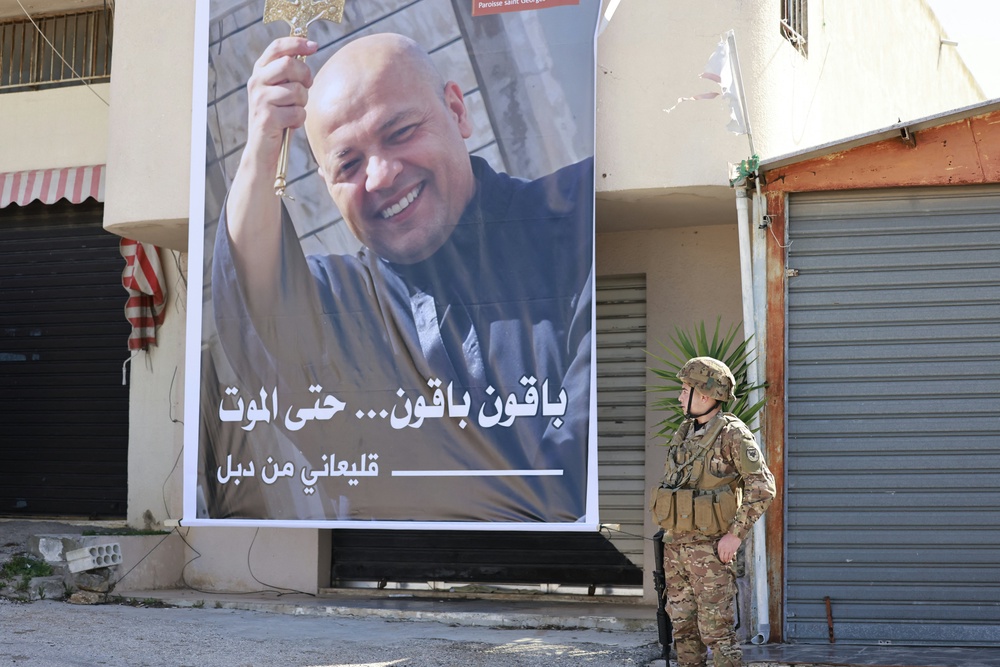 A Lebanese army soldier stands next to a poster of Father Pierre al-Rahi during his funeral (AFP/Getty)