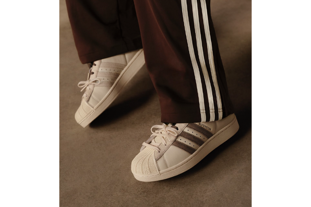 The white superstar trainers feature brown panelling (Adidas)
