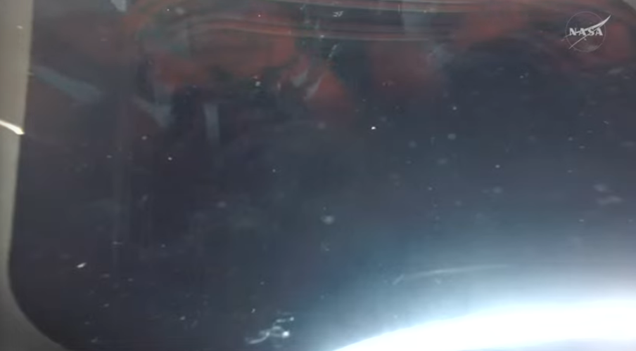 The reflection of Artemis II astronauts in the window of the Orion spacecraft on 10 April, 2026 (Nasa)
