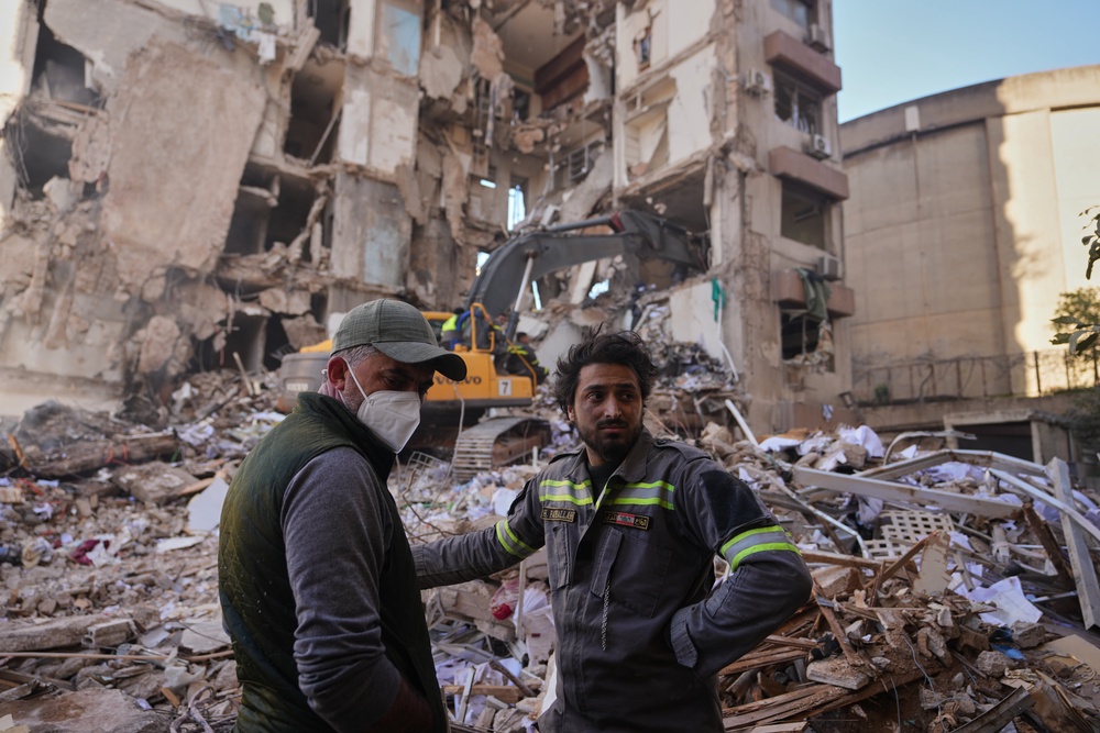 A Lebanese civil defense worker, right, stands with a resident at the site of a building destroyed in an Israeli airstrike in Beirut, Lebanon (AP)