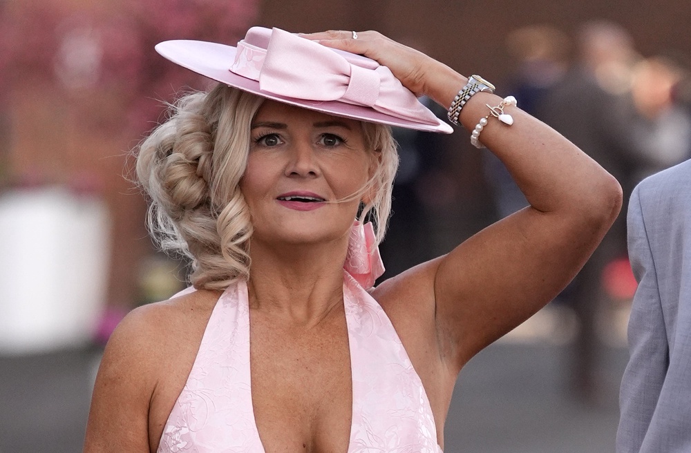 A racegoer holds on to her hat at Aintree racecourse (Peter Byrne/PA) (PA Wire)